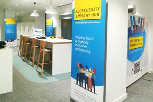 The interior of one of the accessibility empathy hubs showing brightly coloured banners and high stools at a raised desk